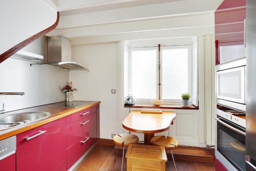 une cuisine avec des placards rouges et une table en bois dans l'établissement Écrin Privé au Parc Monceau, à Paris