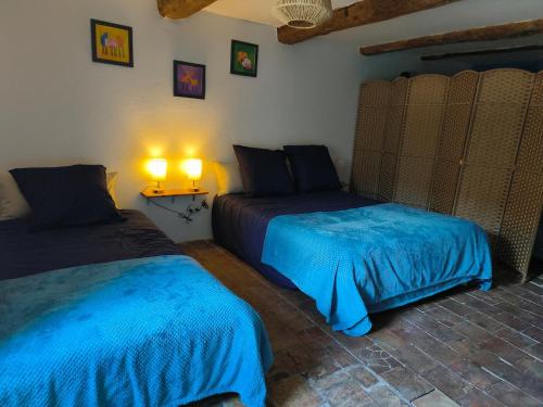- une chambre avec 2 lits avec des draps bleus et une lampe dans l'établissement Mas de Chalvagne Gite confortable pour 5 personnes, à Val-de-Chalvagne