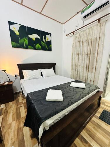 a bedroom with a bed with black sheets and white pillows at Meraathanam in Jaffna