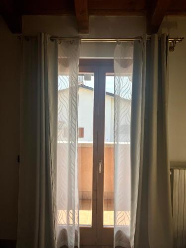 a window with white curtains in a room at Casa Davide in Castelnuovo del Garda