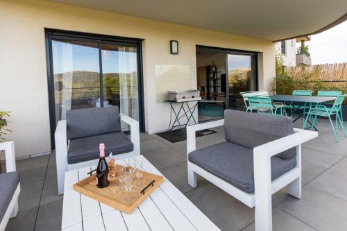 - une terrasse avec 2 chaises et une table avec des verres à vin dans l'établissement La Clé Terrasse, Proche port,centre, parking,clim, à Porto-Vecchio