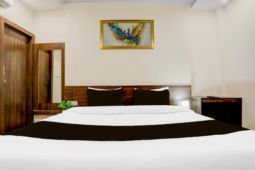 a bedroom with a large white bed and a picture on the wall at Hotel O Ganga Niwas in Prayagraj
