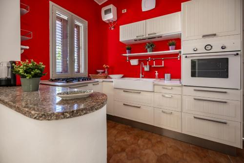 a red kitchen with white cabinets and a counter at Villa Carmela Arenella in Arenella