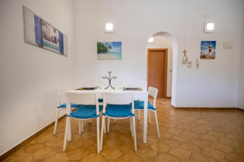 a dining room with a white table and blue chairs at Villa Carmela Arenella in Arenella