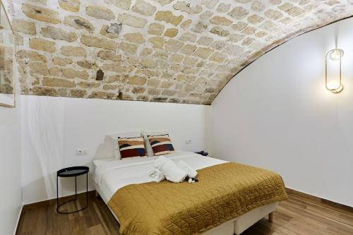 une chambre avec un lit avec un mur en pierre dans l'établissement Duplex in the center of Paris, à Paris
