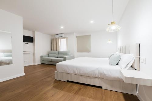 a white bedroom with a large bed and a couch at Hotel Casa Jazmin in Granada