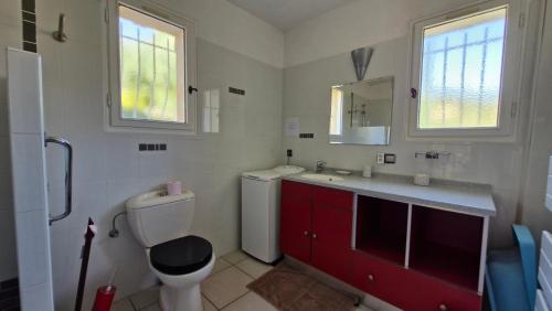 La salle de bains est pourvue de toilettes, d'un lavabo et de placards rouges. dans l'établissement L'éveil Marin, à Roquebrune-sur Argens