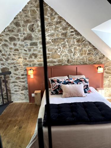une chambre avec un lit avec un mur en pierre dans l'établissement Petite maison de charme, à Châtelaudren-Plouagat