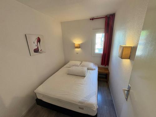 une petite pièce avec un lit et une fenêtre dans l'établissement Appartement - Cap d'Agde, au Cap d'Agde