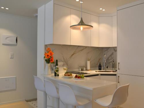 a kitchen with white cabinets and a white table and chairs at HausKomma 서울 홍대,이태원,명동 짐보관 무료 주차 엘레베이터 새아파트 in Seoul