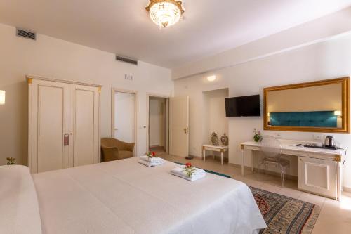 a bedroom with a white bed and a desk at Hotel Parco delle Fontane in Siracusa