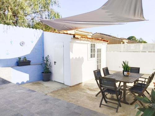 a patio with a table and chairs and a white fence at Casa Robles, casa con piscina y barbacoa in Partida de La Cañada