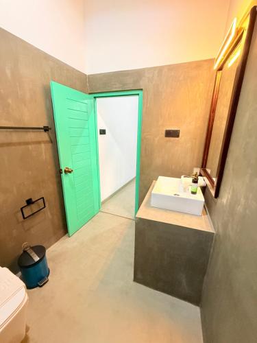 a bathroom with a green door and a sink at Calm Side Villa Hikkaduwa in Hikkaduwa