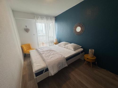 une chambre avec un grand lit avec un mur bleu dans l'établissement L'Échappée Vendéenne - T2 cosy en bord de mer, à Saint-Hilaire-de-Riez
