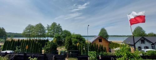 a red and white flag flying next to a house at Lubuskie jezioro in Wilkowo