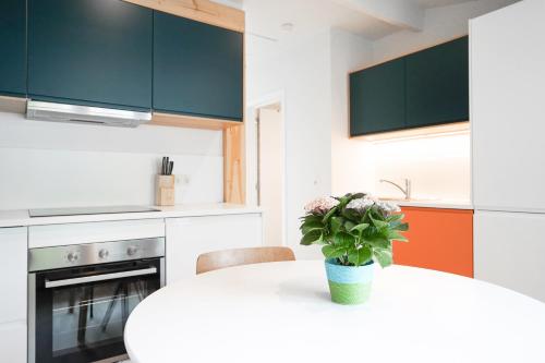 a kitchen with a white table with a vase of flowers on it at Gîte d'artiste, Riverside in Tilff