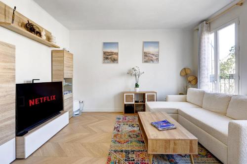 un salon avec un canapé blanc et une télévision dans l'établissement Flat de luxe a Republique avec terrasse, à Paris