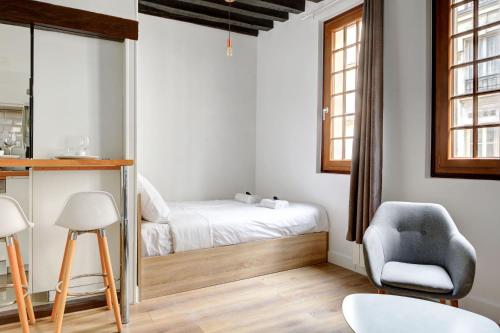 une petite chambre avec un lit et une chaise dans l'établissement Luminous flat in le marais, à Paris