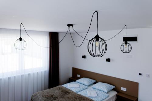 a bedroom with three lights hanging above a bed at Villa Oliver Lenti in Lenti