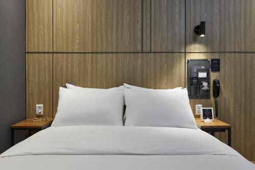 a bed with white pillows in a hotel room at Justsleep hotel Cheonan Dujeong branch in Cheonan