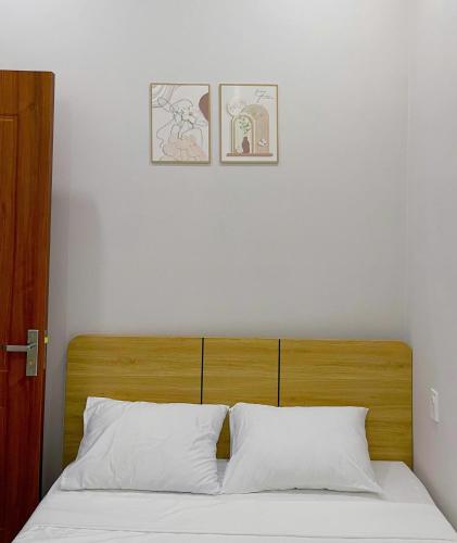 a bed with two white pillows and two pictures on the wall at Adora Homestay Hue in Hue