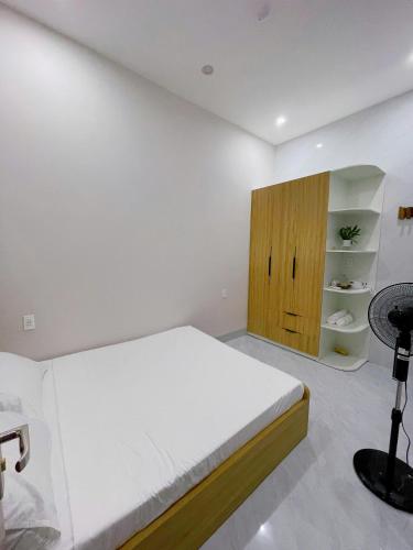 a white bedroom with a bed and a wooden cabinet at Adora Homestay Hue in Hue