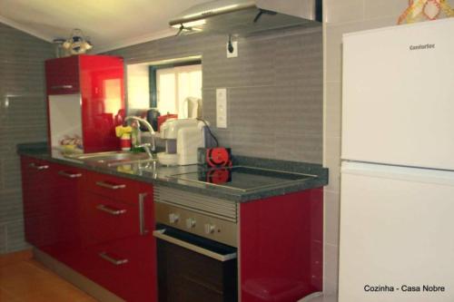 a kitchen with red cabinets and a white refrigerator at Retiro na Natureza - Casa com piscina in Digueifel