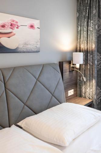 a bedroom with a bed with a headboard and a lamp at Hotel Ganslhof - Adults only in Salzburg
