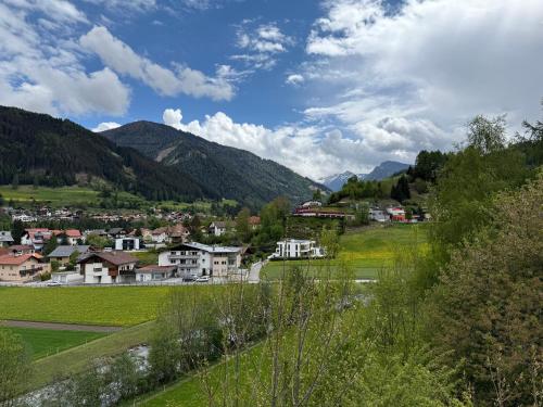 a town in the mountains with a green field at Auszeit im Holzhaus in Steinach am Brenner