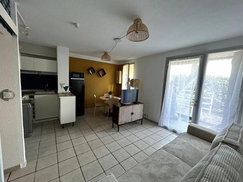 un salon avec une cuisine et une table avec une télévision dans l'établissement Jolie T2 avec terrasse proche plage, à Soulac-sur-Mer