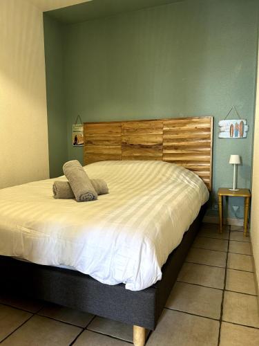 une chambre avec un grand lit avec une tête de lit en bois dans l'établissement Jolie T2 avec terrasse proche plage, à Soulac-sur-Mer