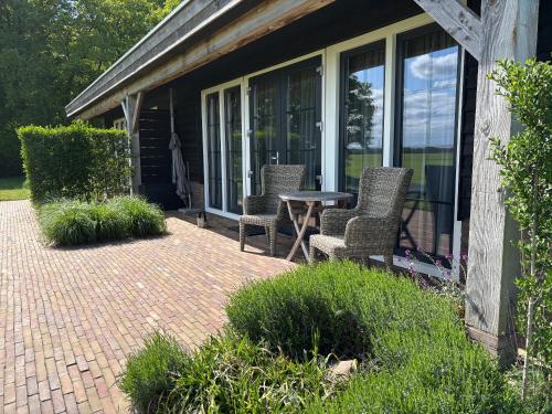 a patio with chairs and a table and windows at Hof van Lenthe appartement De Mars in Dalfsen