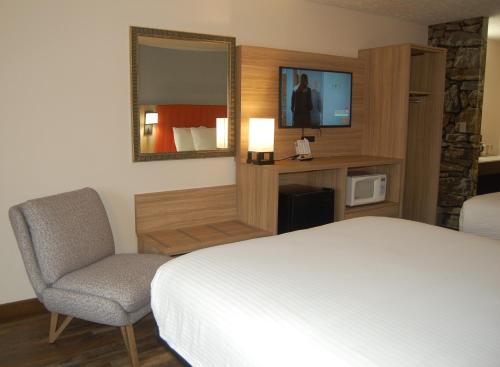 a bedroom with a bed and a chair and a television at Vacation Lodge in Pigeon Forge