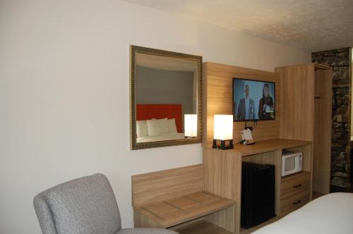 a room with a bed and a mirror and a chair at Vacation Lodge in Pigeon Forge