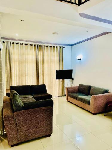 a living room with two couches and a television at bawana vila in Uswetakeiyawa