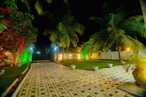 a courtyard with palm trees at night with green lights at bawana vila in Uswetakeiyawa