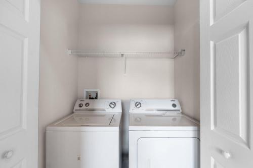 a white laundry room with two machines and a door at A hidden Gem in plain sight in Orlando