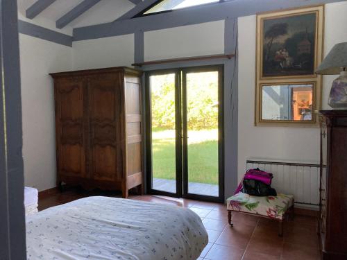 - une chambre avec un lit et des portes coulissantes en verre dans l'établissement maison dans les landes avec piscine, à Trensacq
