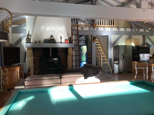 un salon avec une cheminée et une piscine dans l'établissement maison dans les landes avec piscine, à Trensacq
