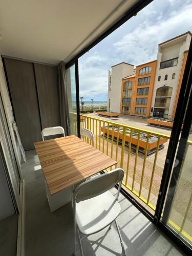 Elle comprend un balcon avec une table et des chaises en bois. dans l'établissement T2 front de mer secteur Lydia- Clim, au Barcarès