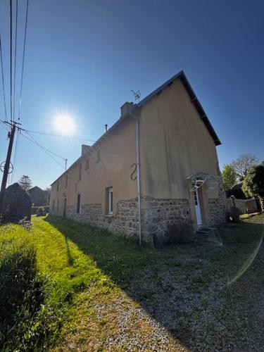 un ancien bâtiment en pierre situé sur le côté d'une route dans l'établissement Maison normande tout confort, à Saint-Michel-de-la-Pierre