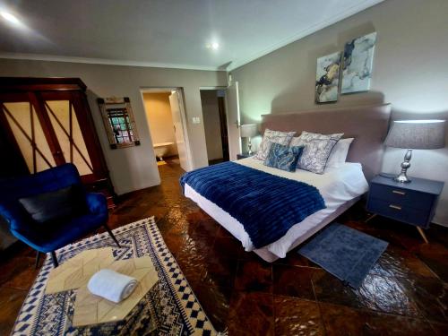 a bedroom with a bed with a blue blanket and a chair at Remi Lodge in Dullstroom