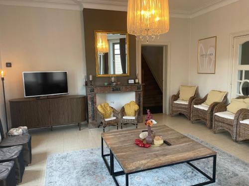 Villa Dageraad في دي بان: غرفة معيشة مع طاولة وتلفزيون