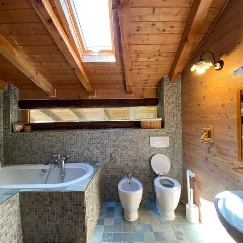 a bathroom with a tub and a toilet and a sink at Chalet Giulia in Bezzecca
