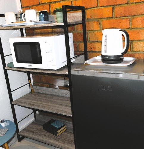 a microwave sitting on a shelf next to a refrigerator at Tanya's Haven Guesthouse in Klerksdorp