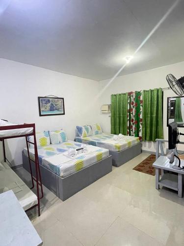 two beds in a room with green curtains at Mario's Travellers Inn in Coron