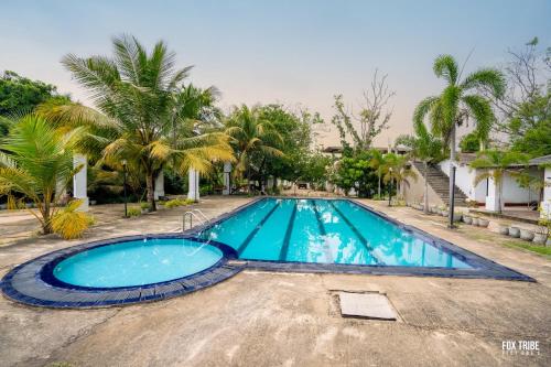 a large blue swimming pool with palm trees at Riverside Hotel in Katunayake
