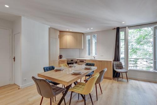 une cuisine et une salle à manger avec une table et des chaises en bois dans l'établissement 563 Suite Maillot - Superbe Appartement à Paris, à Paris