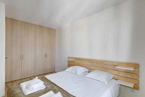 - une chambre avec un lit blanc et une tête de lit en bois dans l'établissement 563 Suite Maillot - Superbe Appartement à Paris, à Paris