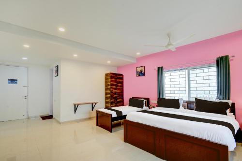 two beds in a room with a pink wall at Super Hotel O SRI NIRVANA PLAZA in Gachibowli
